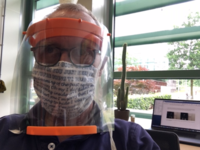 Facial shield made of acetate (overhead projector sheets, 0.1 mm thickness), and a fitting plastic head band (orange; with an elastic strip at the back, not shown). top, with mouth-mask; bottom: without (as recommended by Radboudumc). The facial shield can be easily put on or taken off by lifting the elastic strip at the back, without having to touch the face, or the shield. Later, the shield can be thoroughly cleaned for re-use.